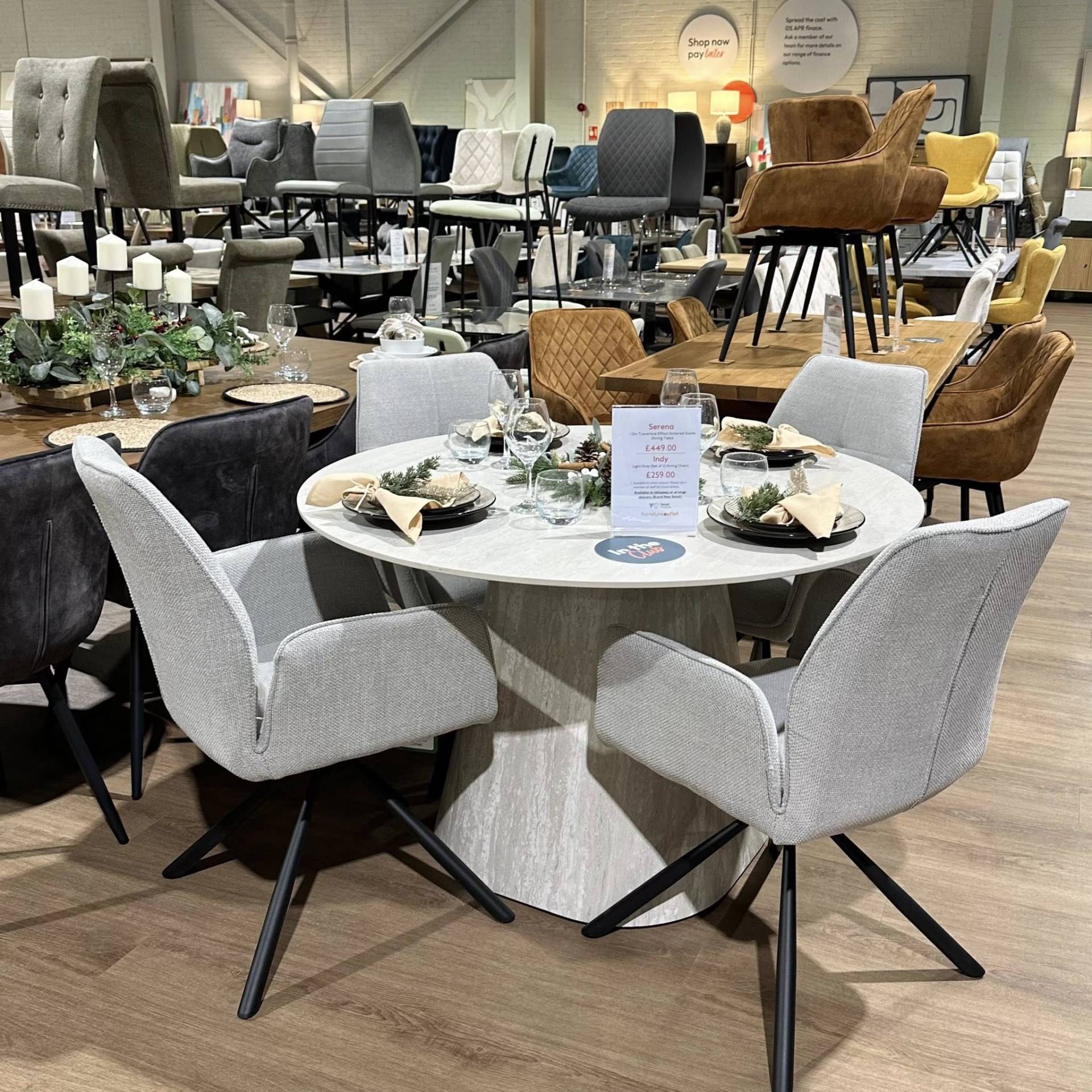 Serena round travertine stone table with grey Indy swivel chairs. A smart, sturdy set at Furniture Outlet Colchester