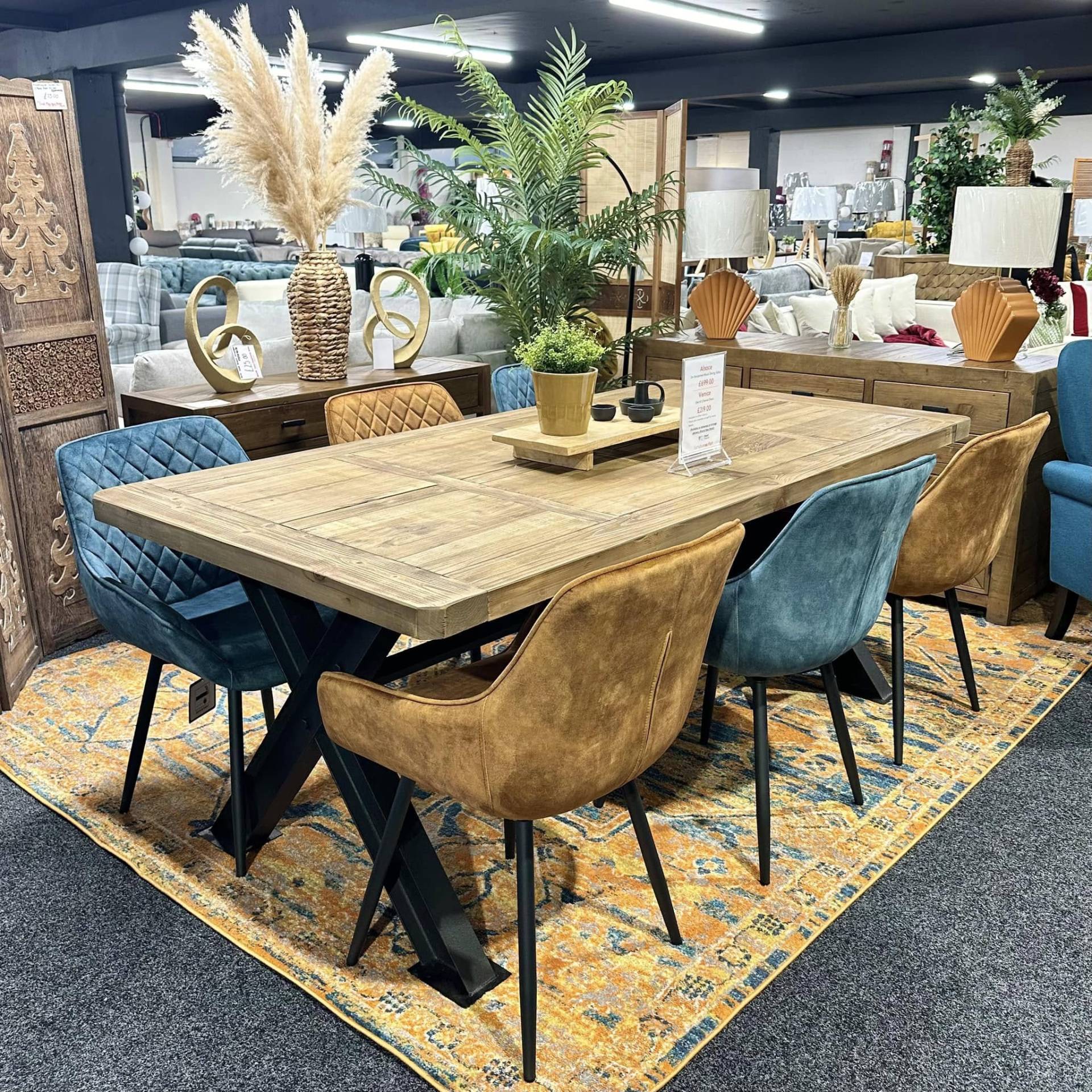 Modern dopamine decor dining setup with a wooden table, teal and burnt orange mismatched chairs and warm textured accessories