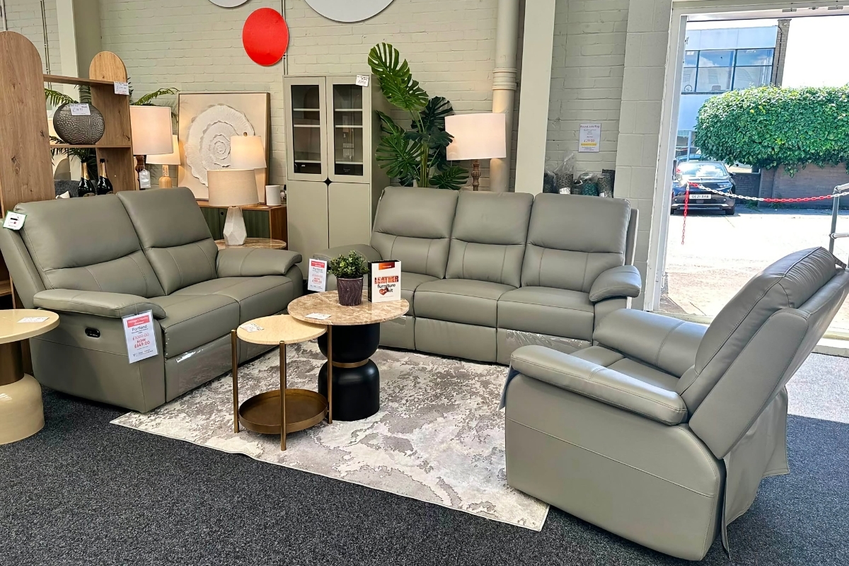 Portland grey leather recliner set arranged in a bright Furniture Outlet showroom with round marble tables, soft lighting and modern decor